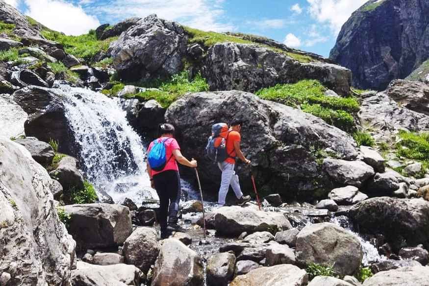 Trekkers crossing waterfall of Hampta valley