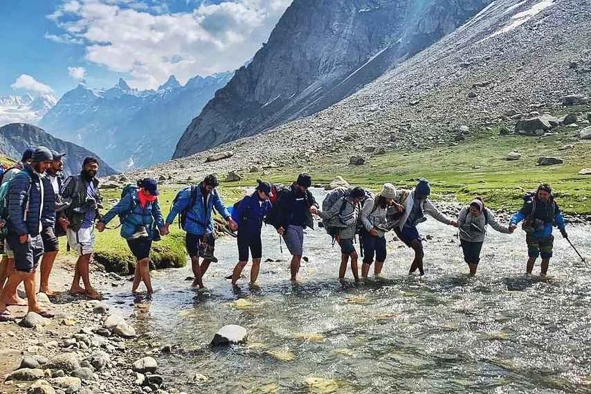 Trekkers crossing water stream